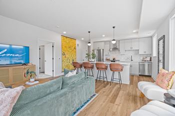 a living room with a couch and a kitchen with bar stools